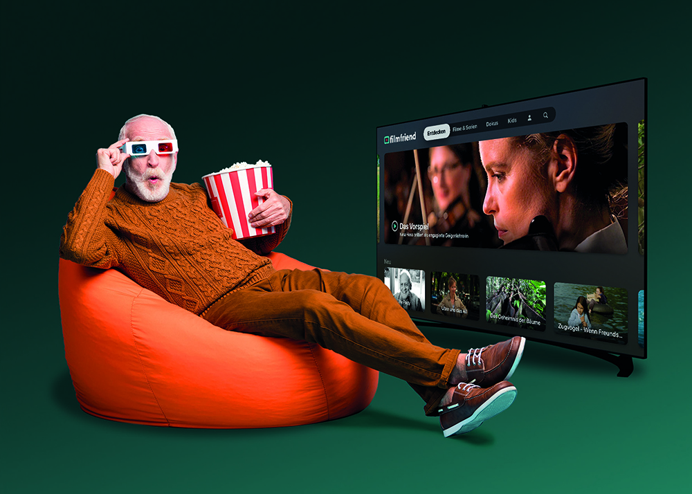 Mann mit 3D-Brille und Popcorn auf einem Sitzsack vor einem SmartTV